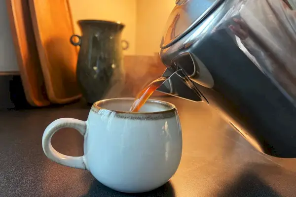 Osoba nalévá kávu z kávovaru Cook N Home 8-Cup Coffee Percolator do hrnku