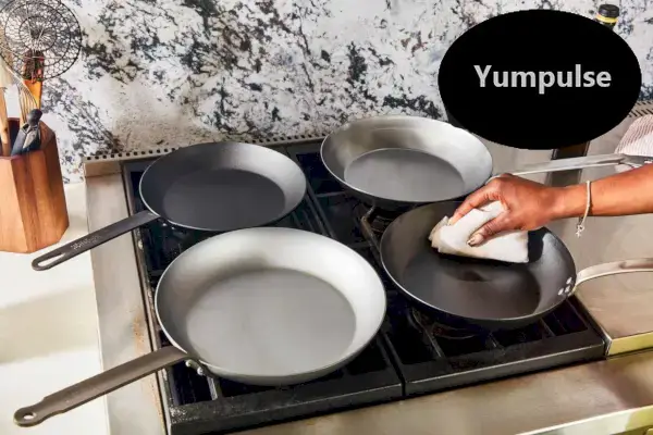 Wycieranie ręczne najlepszych patelni ze stali węglowej wyświetlanych na płycie kuchennej