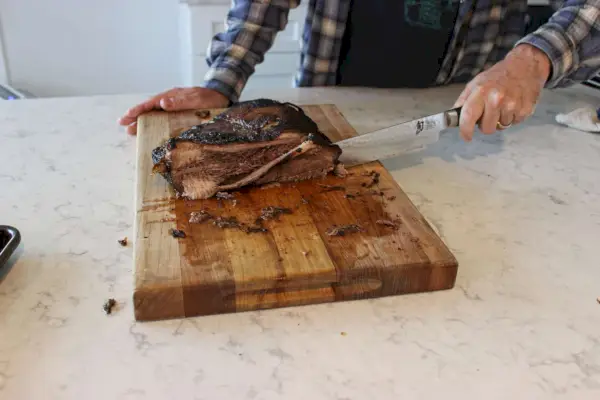Eine Person verwendet das Shun Premier Tranchiermesser- und Fleischgabel-Set zum Schneiden von Fleisch
