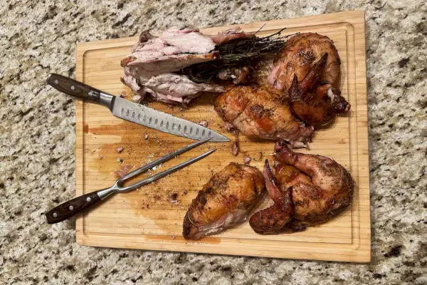 Messermeister Avanta 2-teiliges Tranchierbesteck auf einem Schneidebrett neben einem zerschnittenen Huhn