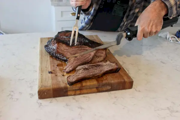 Eine Person verwendet das elektrische Messer von BLACK+DECKER, um Fleisch zu schneiden