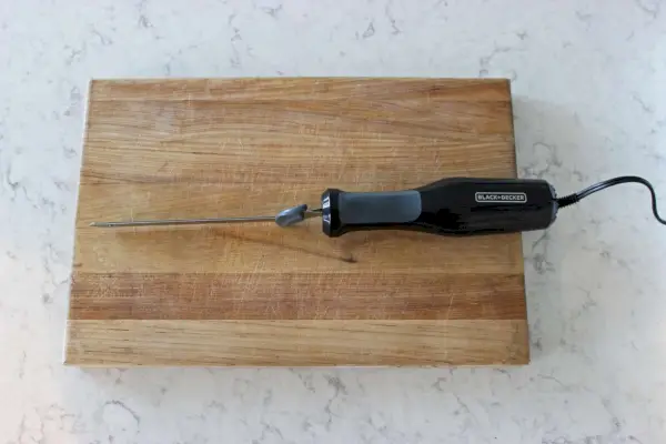 Das BLACK+DECKER Elektromesser auf einem Holzschneidebrett