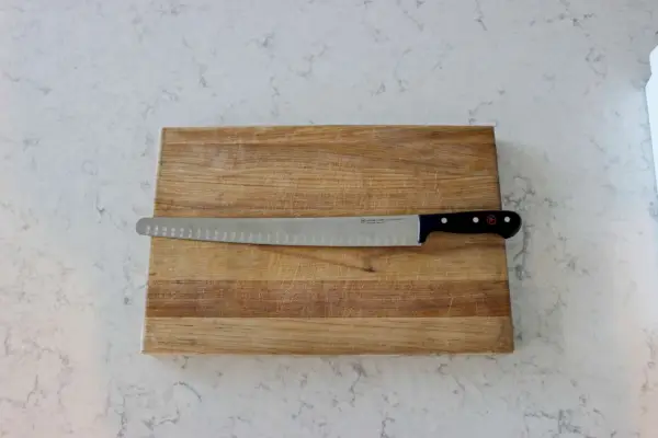 Das Wüsthof Gourmet 14-Zoll-Brustmesser mit hohler Kante auf einem Holzschneidebrett