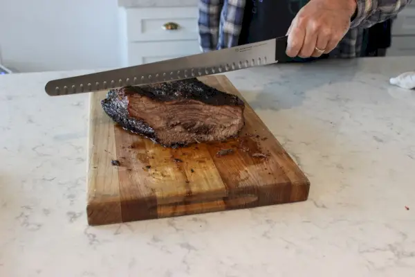 Eine Person schneidet Bruststück mit dem Wüsthof Gourmet 14-Zoll-Brustmesser mit hohler Kante