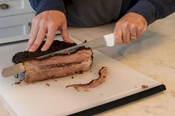 Eine Person schneidet Fleisch mit dem 12-Zoll-Slicer von Dexter-Russell