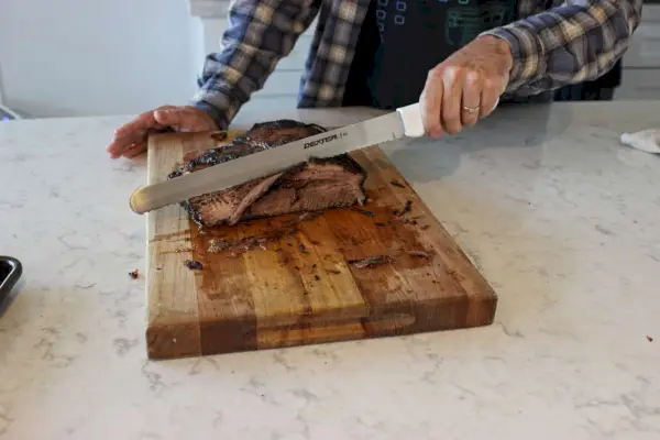 Eine Person verwendet den Dexter-Russell 12-Zoll-Slicer zum Schneiden von Fleisch