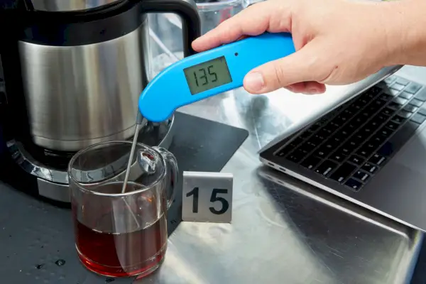 pessoa medindo a temperatura do café ao lado da cafeteira de gotejamento especial Café