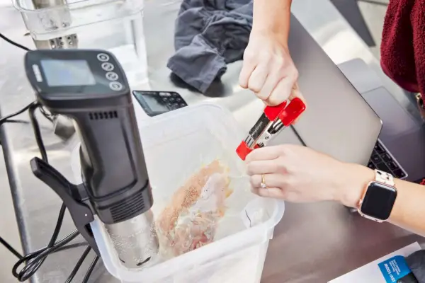 Person versiegelt ein Lebensmittelpaket vor dem Inkbird Sous Vide Precision Cooker ISV-100W