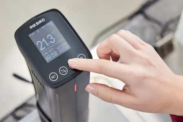 Nahaufnahme einer Person, die einen Knopf des Inkbird Sous Vide Präzisionskochers ISV-100W drückt