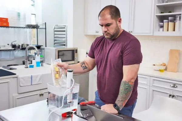 Person kocht Essen im Testeimer mit dem Breville Joule Sous Vide