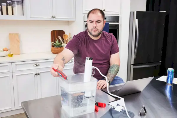 Person testet die Wassertemperatur in einem Eimer mit dem Breville Joule Sous Vide