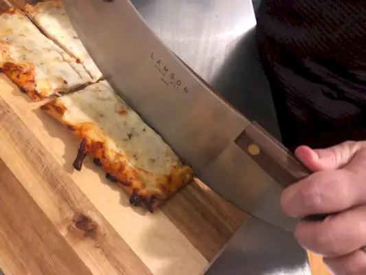 אדם שמשתמש ב-Lamson Pizza Rocker כדי לחתוך פיצה