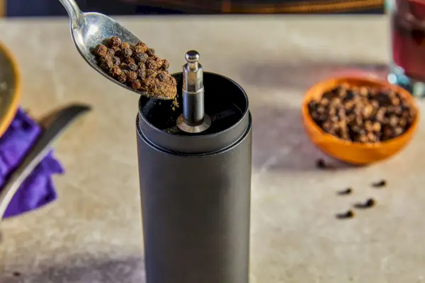 Osoba držící mlýnek na pepř a koření FinaMill nad kuchyňskou linkou