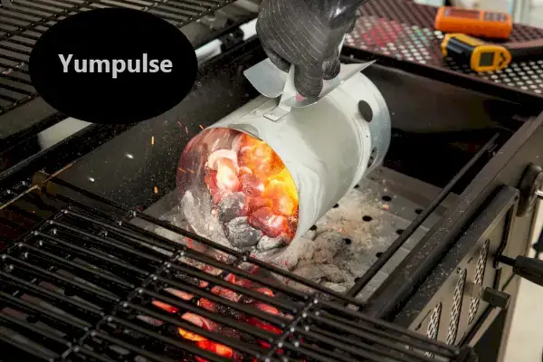 Eine Person schüttet heiße Kohlen in einen Holzkohlegrill im klassischen Karrenstil von Char-Griller