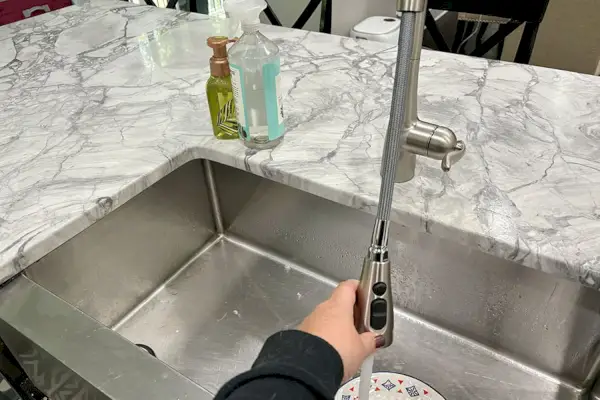 Osoba używa bezdotykowego rozpylacza wyciąganego Moen 7594EVC Arbor Smart Faucet