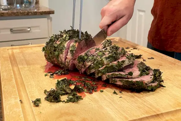 Mano usando el juego de cuchillo para trinchar y tenedor para carne Shun Premier para cortar un asado