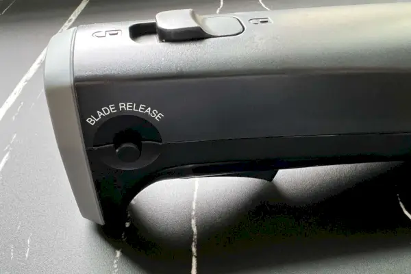 Primer plano de los botones de bloqueo y liberación de la hoja del juego de cuchillos eléctricos con tabla de cortar Cuisinart CEK-41