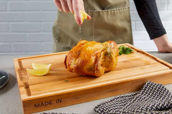 אדם סוחט לימון על עוף על קרש חיתוך Made In The Butcher Block