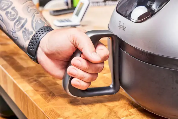Mano levantando una bandeja sucia de la canasta Cosori Smart Air Fry de 4 cuartos