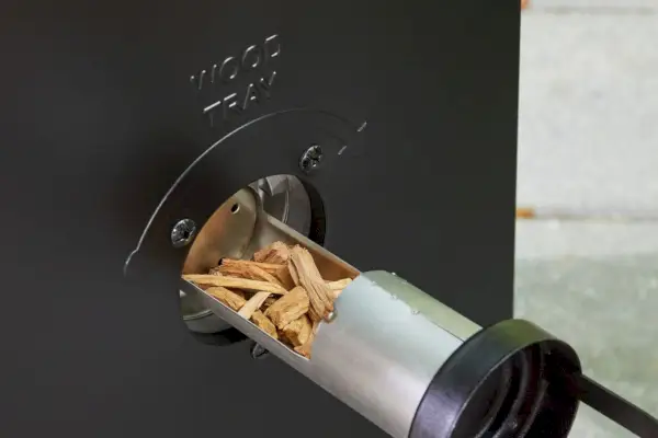 Les copeaux de bois sont placés à l'intérieur du fumoir électrique numérique Masterbuilt de 30 pouces, noir (MB20070421)