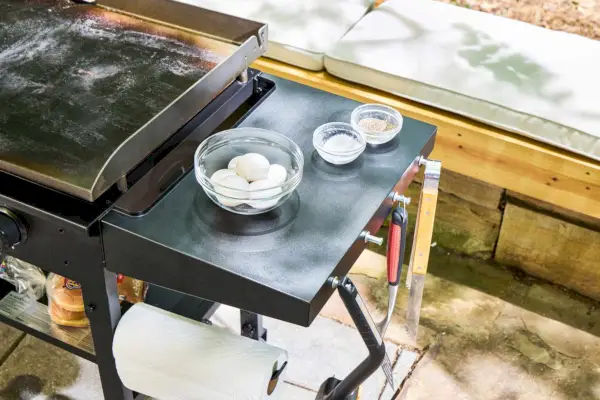 Huevos y condimentos en la mesa auxiliar de la parrilla de gas Blackstone 1554 Cooking de 4 quemadores con superficie plana