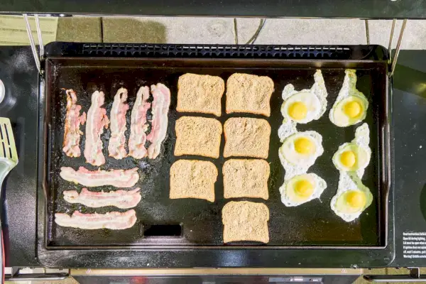 Huevos, tocino y tostadas francesas se cocinan en la Traeger Flatrock Flat Top Grill