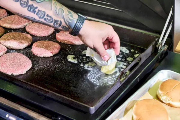 Uma pessoa derrete manteiga no Traeger Flatrock Flat Top Grill