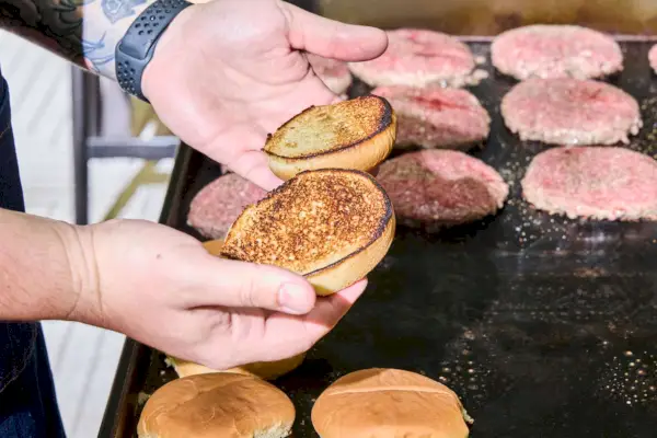 Los panecillos de hamburguesa se tuestan en la parrilla de gas con tapa plana de 4 quemadores Blackstone 1554 Cooking