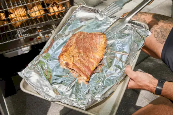 אדם מסיר בשר מבושל מהמעשן החשמלי האנלוגי Char-Broil (18202077)