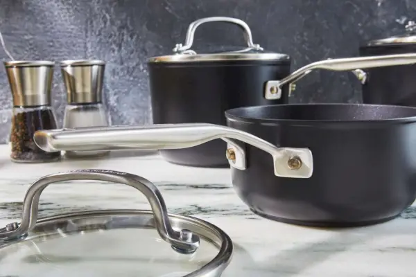 Nahaufnahme des hartanodisierten 10-teiligen Antihaft-Kochgeschirrsets von KitchenAid mit Topf und Deckel auf der Arbeitsplatte