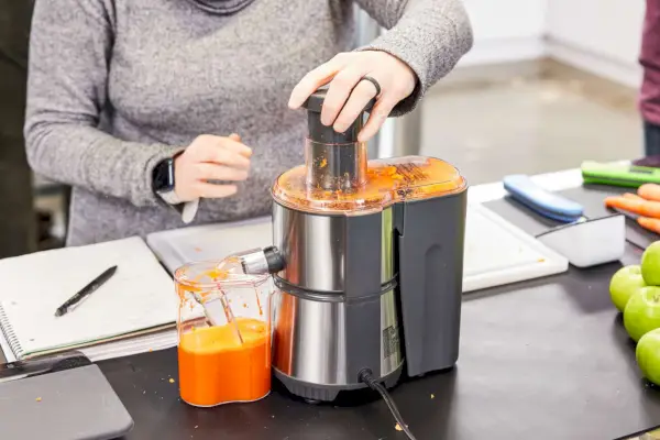 Osoba wyciskająca sok z marchwi przy użyciu fontanny Breville Juice Fountain Elite