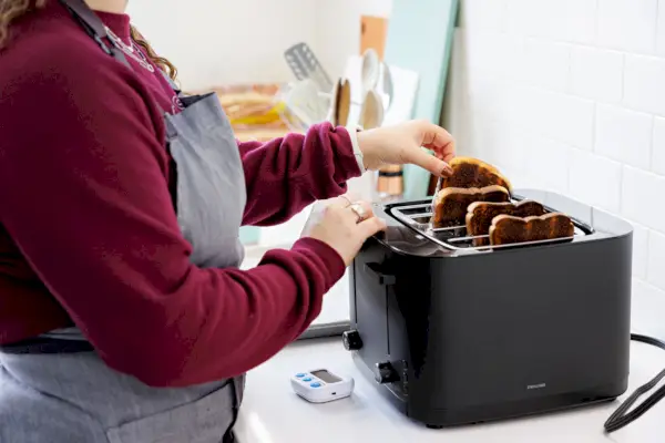 Person zieht geröstetes Brot aus dem Zwilling Enfinigy Cool Touch 4-Scheiben-Toaster