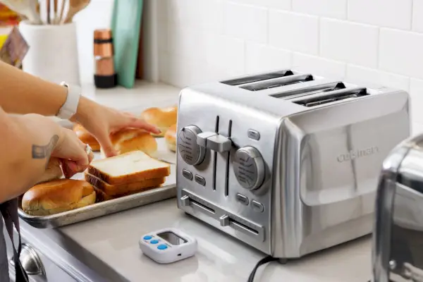 Frau benutzt den Cuisinart CPT-640 4-Scheiben-Toaster aus Metall zum Toasten von Brot