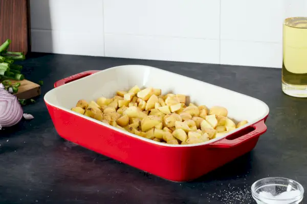Prostokątne ceramiczne naczynie do pieczenia Red Staub wypełnione ziemniakami, ustawione na blacie