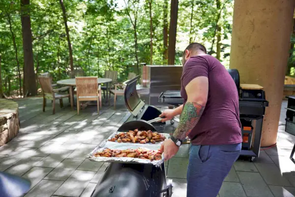 Persona che condisce il pollo davanti a un Louisiana Grills 1000 Black Label Series Grill