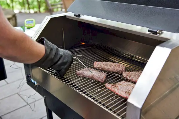 Persona che utilizza una sonda di temperatura durante la cottura della carne in un grill a pellet Recteq