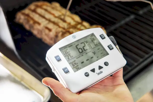 Osoba posiadająca zdalny termometr alarmowy dymu ThermoWorks do grillowania