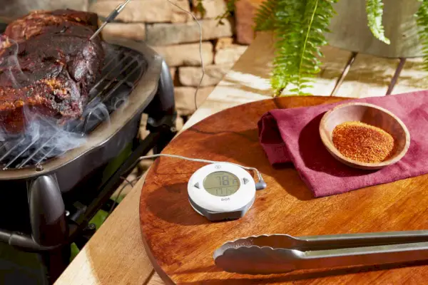 Prosty termometr alarmowy ThermoWorks DOT znajduje się na stole wraz z grillem obok