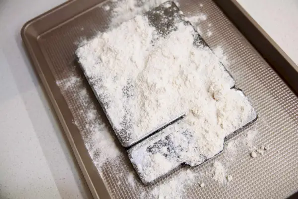 Dobre chwyty OXO 11 funtów. Waga spożywcza ze stali nierdzewnej z wysuwanym wyświetlaczem, posypana mąką i umieszczona w formie do pieczenia