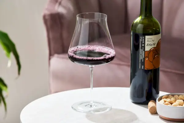 병 옆에 레드 와인이 채워진 Zenology Somm Pinot Noir 손으로 불어 만든 와인 잔