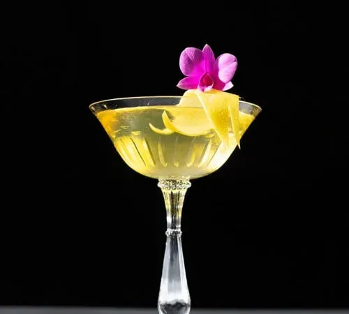 Leuchtend gelber Cocktail in einem Coupé-Glas.' title=