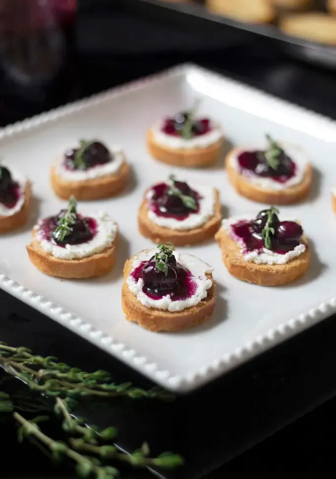 ヤギのチーズ、ブルーベリーのコンポート、タイムを添えた小さなクロスティーニのプレート' loading='lazy' title=