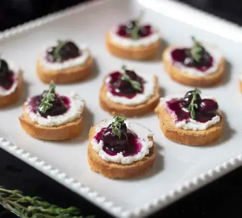 ヤギのチーズ、ブルーベリーのコンポート、タイムを添えた小さなクロスティーニのプレート' title=