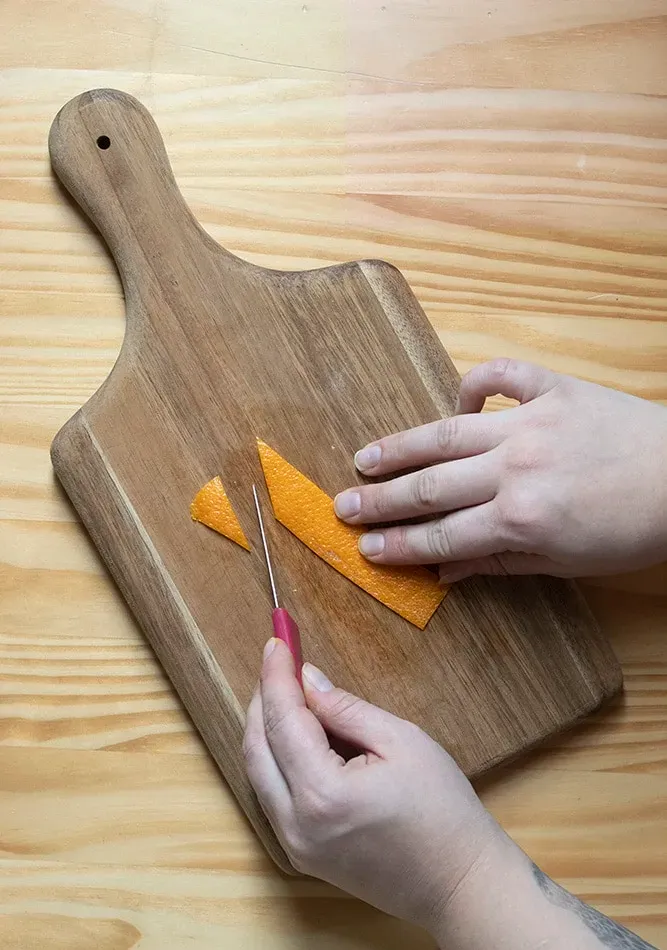 ein heller Cocktail mit weißem Schaum und einer ausgefallenen Garnitur aus geschnittener Orangenschale' title=
