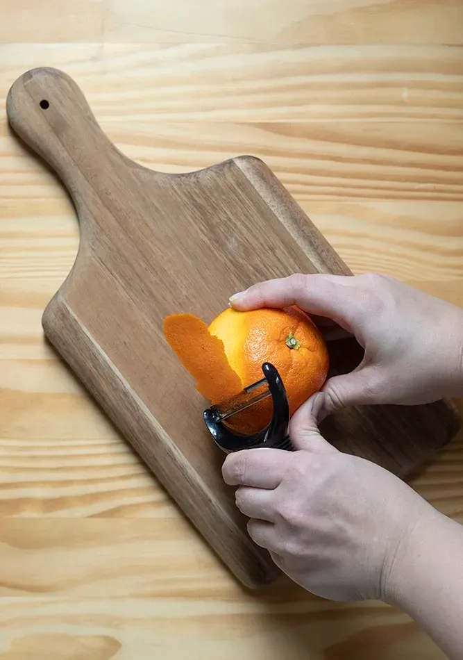 Eine Orange mit einem Gemüseschäler schälen' title=