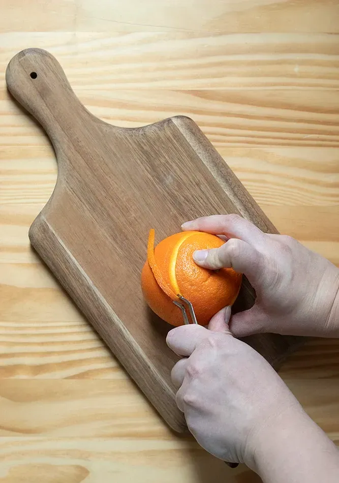 Mit einem Kanalmesser einen Streifen Orangenschale schälen' title=