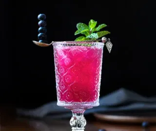 un cóctel de color rosa brillante con menta y una cucharada de arándanos.' loading='lazy' title=