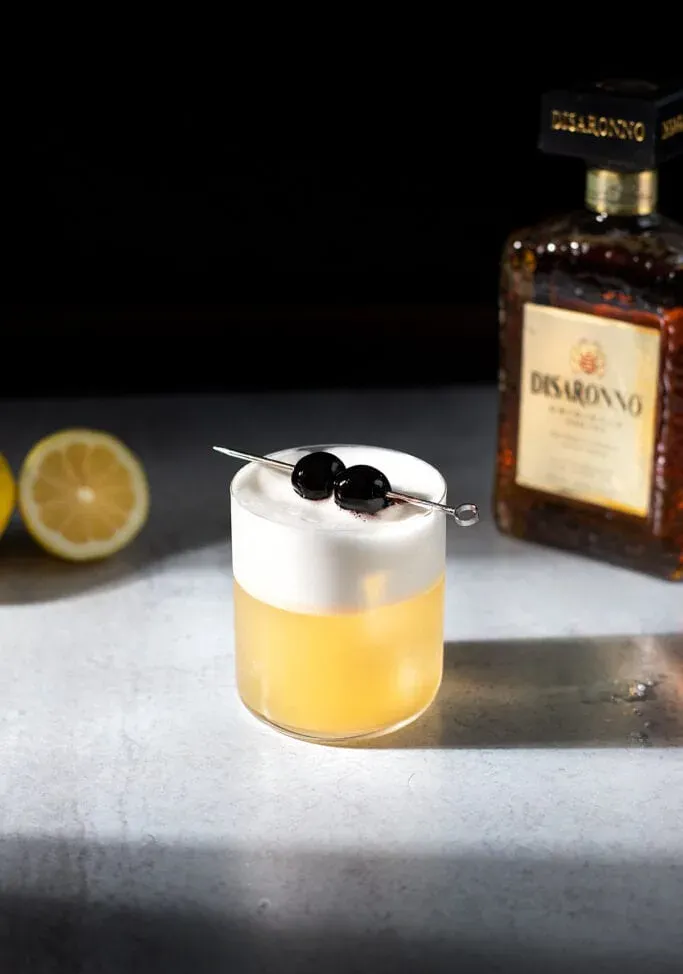 cocktail amaretto aigre avec une bouteille de Disaronno.' title=