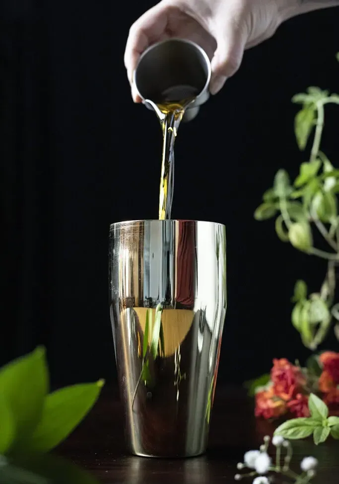 מזיגת וויסקי לתוך שייקר קוקטייל מוזהב' loading='lazy' title=