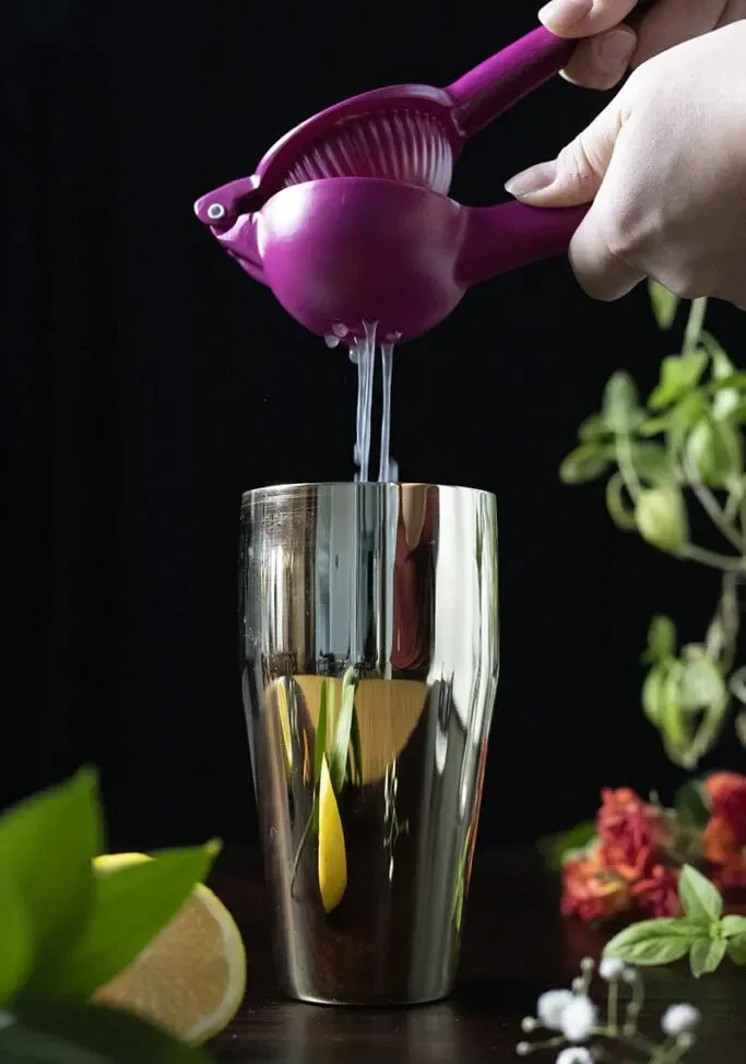 סחיטת מיץ לימון לתוך שייקר קוקטייל מוזהב' title=